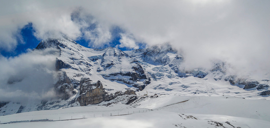 Snow-covered alpine peaks near Jungfraujoch partially hidden by clouds in the Swiss Alps