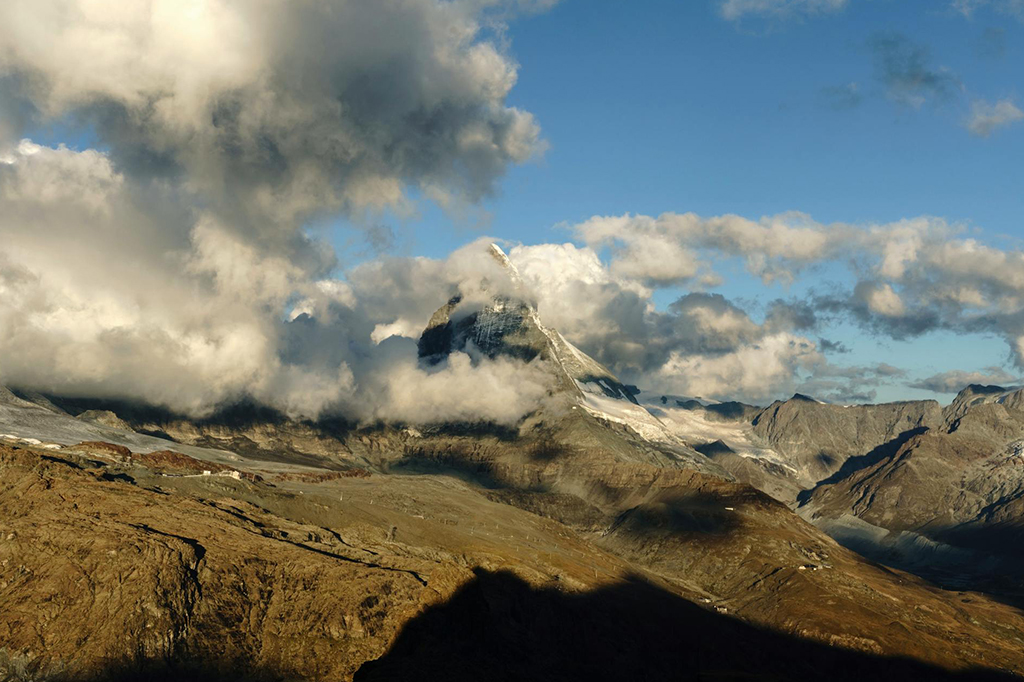 Matterhorn mountain surrounded by clouds and rocky terrain in the Swiss Alps